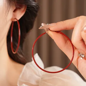 Minimalist deep red round hoop earrings with polished finish shown on a model