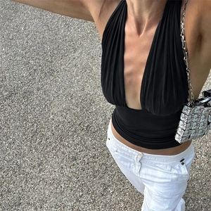 Detail of a black V-neck halter top with pleated design styled with white trousers