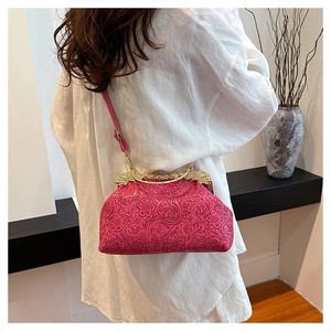 Detail of pink shell-shaped crossbody bag with embossed floral texture and gold clasp