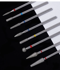 Close-up of 8 assorted diamond nail drill bits with color-coded rings on b&w background