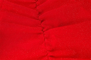 Dettaglio ravvicinato del tessuto a maglia rosso scintillante con eleganti cuciture a pieghe