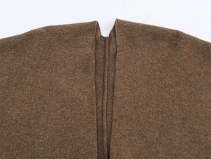 Detailed close-up of brown knit poncho showing thick wool fabric texture and stitching