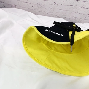 Détail d'un chapeau bob pliable noir et jaune avec cordons ajustables et texte imprimé