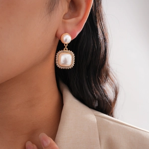 Detail of elegant gold-toned double-layered earrings with white pearls and small crystals