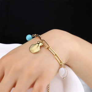 Gold stainless steel shell and natural stone beach bracelet worn on a female wrist