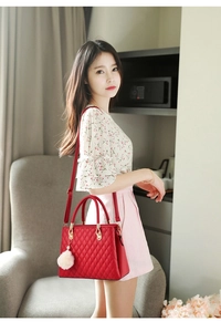 Detail of red quilted PU leather handbag with adjustable strap and beige pom-pom charm
