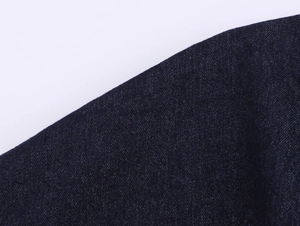 Détail macro du tissu denim bleu foncé montrant la texture sergé de haute densité