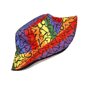 Detailed view of rainbow gradient bucket hat with black heart prints and wide brim