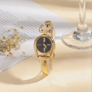 Close-up of vintage golden horseshoe quartz watch with a black dial and roman numerals