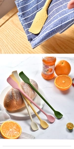 Dual-head silicone scrapers in four colors on a white plate with fresh jam and bread