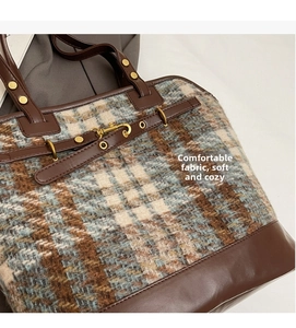 Detail view of large tweed tote bag with leather straps and gold metal hardware studs