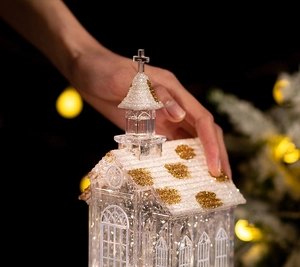 Close-up of a crystal church music box with white snow texture and golden glitter details