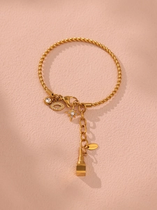 Detail eines vergoldeten Edelstahl-Kabelarmbands mit Stern- und Auge-Anhängern