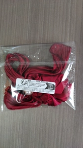 Detail of red satin hair scrunchie with pearl accent inside clear plastic packaging