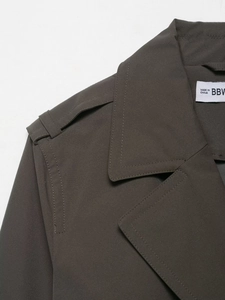 Detail of shoulder epaulettes and collar stitching on dark grey water-resistant trench coat