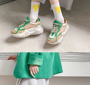 Detail of white heart pattern crew socks paired with green chunky platform sneakers