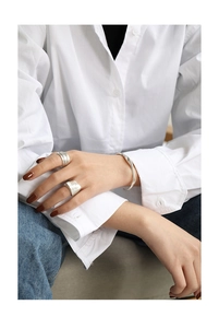 Close-up of minimalist S925 sterling silver hammered rings and slim cuff on woman's hand