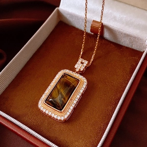 Close-up of tiger eye stone rectangular pendant with pavé crystals in a jewelry box