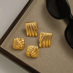 Detailed view of 18k gold plated stainless steel geometric earrings on a woven tray