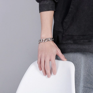 Bracelet gourmette en acier inoxydable poli porté au poignet d'un homme chic