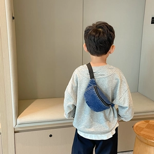 Kid's deep blue denim waist bag with adjustable strap shown worn as a crossbody bag