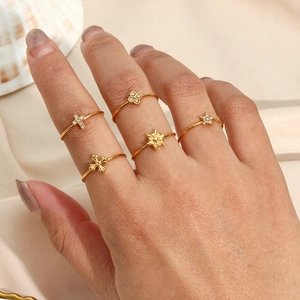 Detail of 18K gold-plated stacking rings set with cross and star charms for women