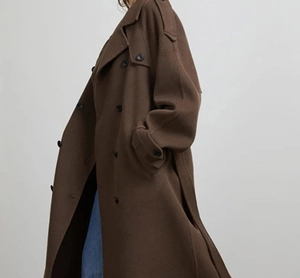 Détails de la texture laine et boutons croisés d'un long manteau marron pour femme