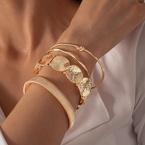 Close-up of four-piece gold geometric bracelets featuring textured bangles on a model