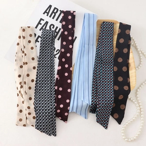 Flat lay of silk-feel scarves with polka dot and geometric patterns on a wooden tray