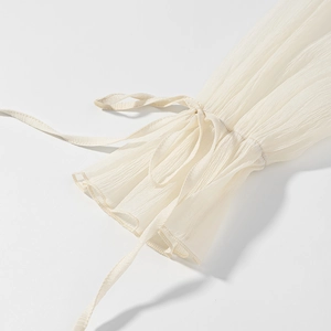 Detailed view of cream chiffon lantern sleeves with delicate pleated texture and tie cuffs