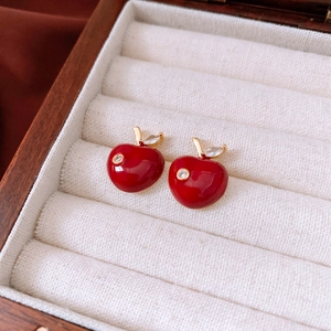 Macro shot of red enamel apple earrings with golden stem and sparkling cubic zirconia