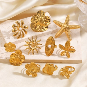 Goldenes Edelstahl-Ring-Set mit Blumen, Sonne und Perlen auf Steinpräsentationsplatte
