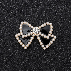 Elegant black enamel bow charm with white faux pearls and a sparkling central crystal