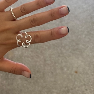 Close-up of 925 sterling silver hollow flower and beaded rings worn on a hand