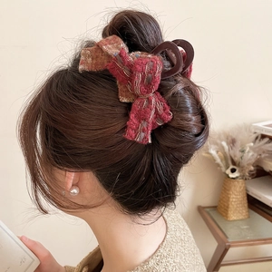 Close-up of a tweed bow hair claw clip styled on hair with fringe detail and warm tones