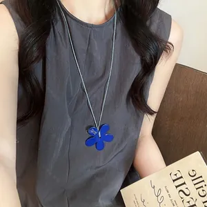 Blue five-petal flower pendant necklace with slim cord shown on a model for styling