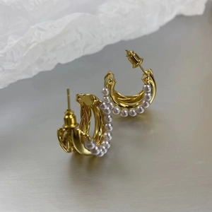 Detailed view of 18K gold plated multi-layer pearl earrings on a metallic surface