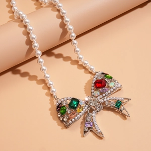 Macro view of crystal bow pendant with multicolor gemstones and white pearl necklace