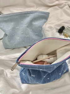 Denim makeup bag set with white embroidered bows and secure zipper closure for travel