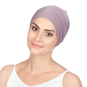 Detailed close-up of a mauve pleated turban headwear on a model with neutral background