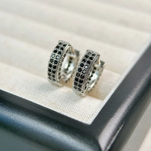 Macro shot of black zircon stones pavé-set on silver hoop huggie earrings