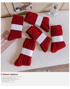Detailed view of five red knitted winter socks with various patterns in a cozy setting