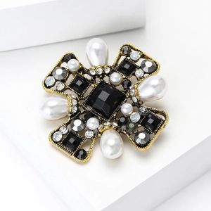 Detail of vintage bronze cross brooch with black gems and white pearls on white background