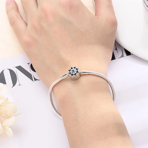 Detailed view of silver snake chain bracelet with snowflake bead on a model wrist