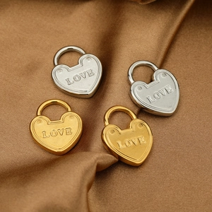 Detailed view of heart-shaped LOVE pendants in gold and silver on brown satin fabric