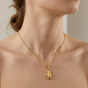 Close-up of a delicate gold boy pendant necklace worn on a woman's collarbone