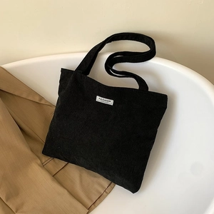 Close-up of black corduroy tote bag with Fashion label inside white minimalist container