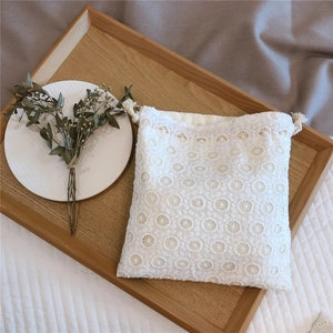 Detailed macro view of white lace drawstring pouch with intricate floral embroidery
