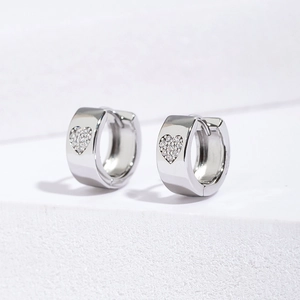Macro shot of silver heart huggie earrings with cubic zirconia pavé and polished metal