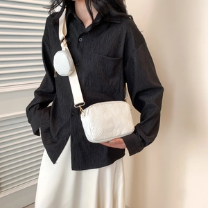 Detail of white crossbody bag with embossed heart patterns and a small round coin purse